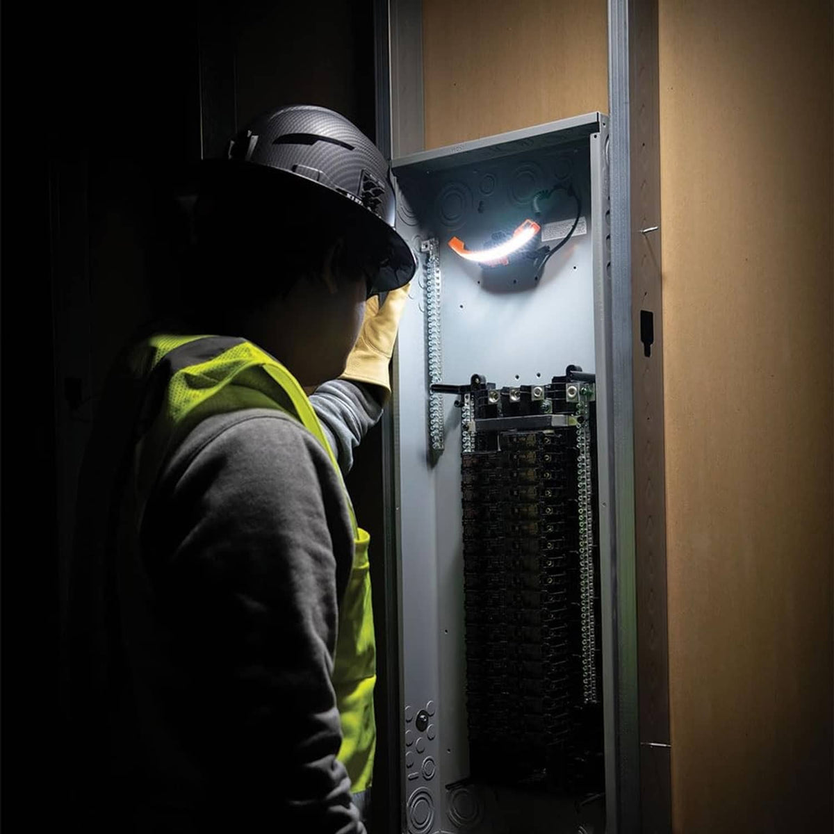 Worker wearing rechargeable LED headlamp illuminating a panel inside doorway