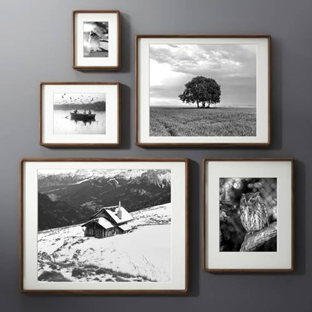 Walnut photo frames with black-and-white prints arranged on wall and tabletop