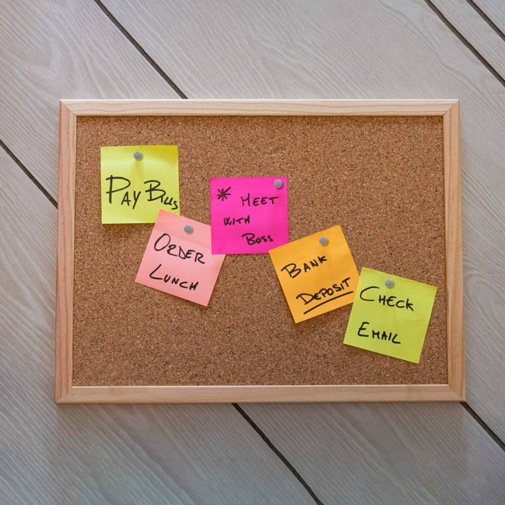 Color sticky notes pinned on a corkboard with gray round-head thumbtacks and gold pins