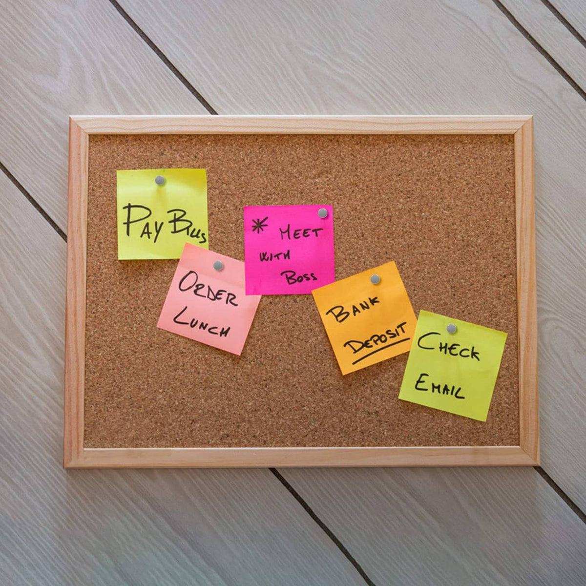 Color sticky notes pinned on a corkboard with gray round-head thumbtacks and gold pins