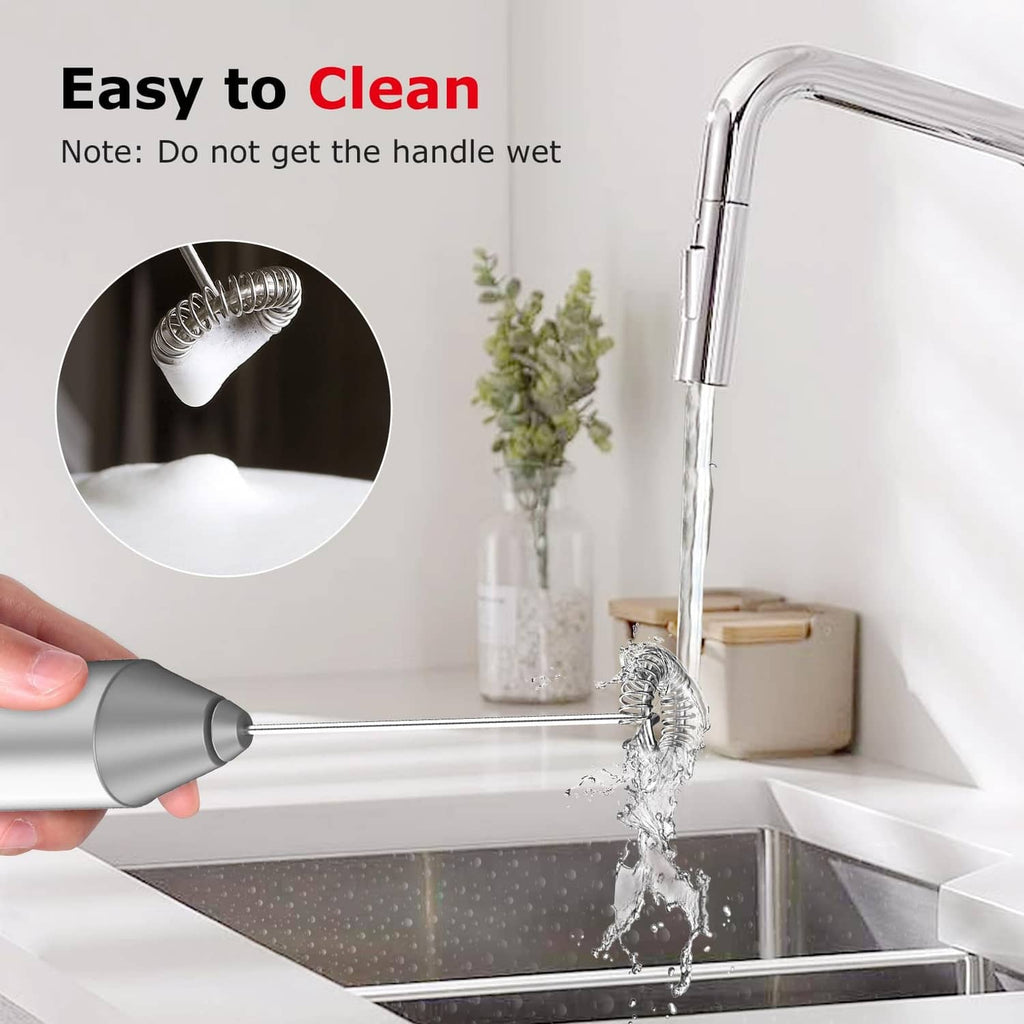 Silver milk frother rinsed under running water at the sink
