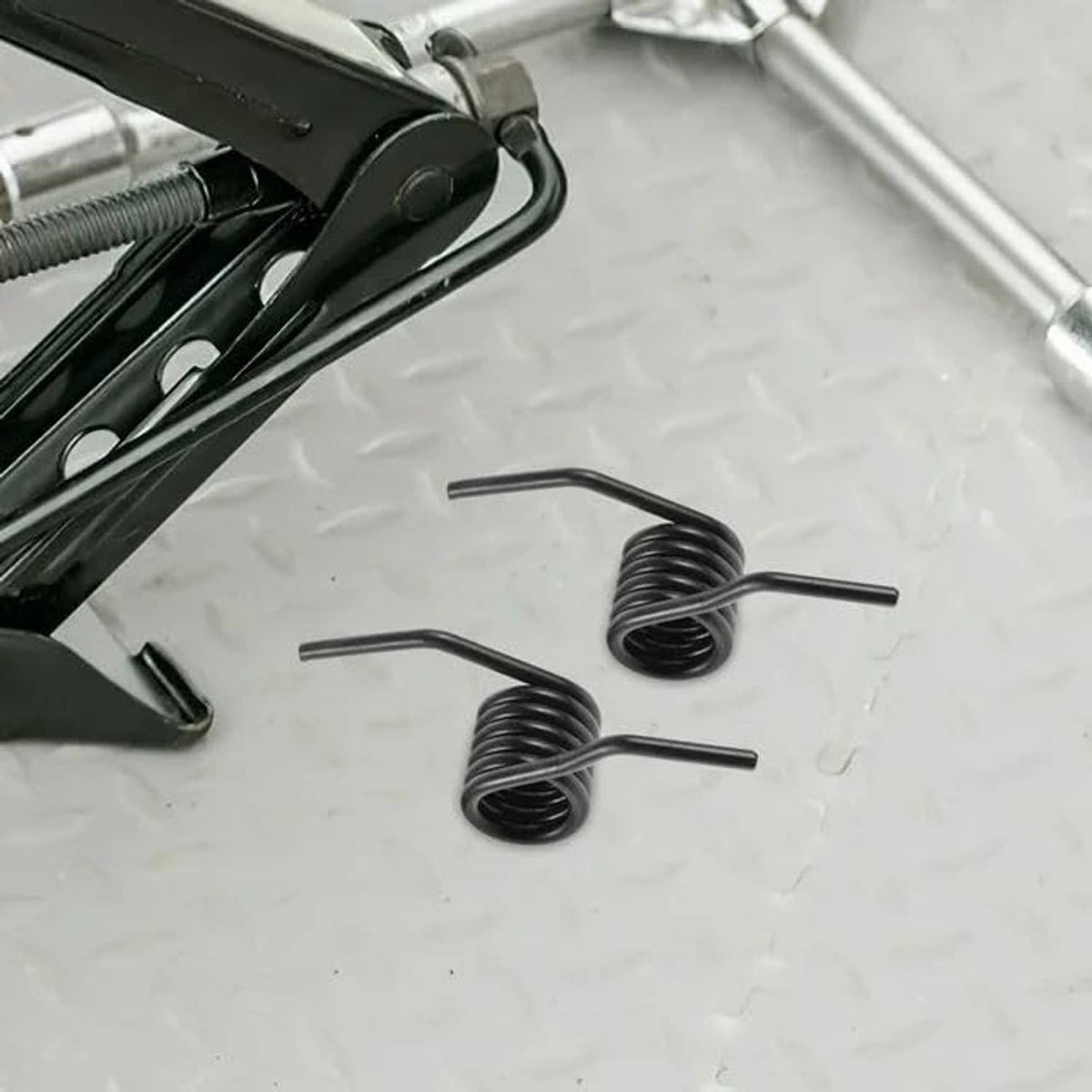 Two black coiled return springs with rod arms, for hydraulic jack handle reset