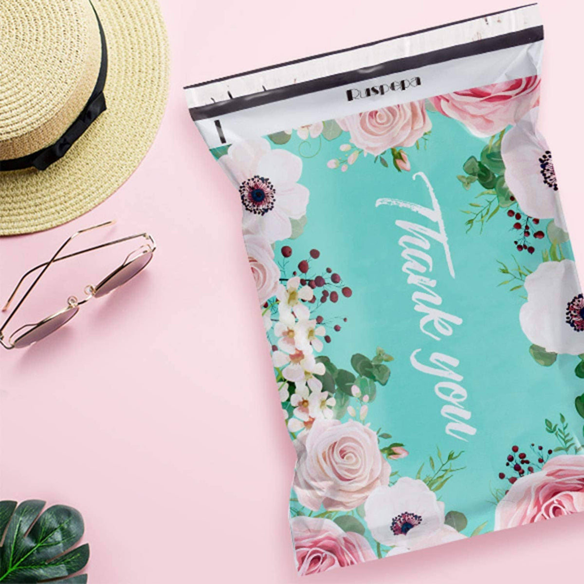 Turquoise floral poly mailer bag with roses and 'Thank you' script, top seal visible
