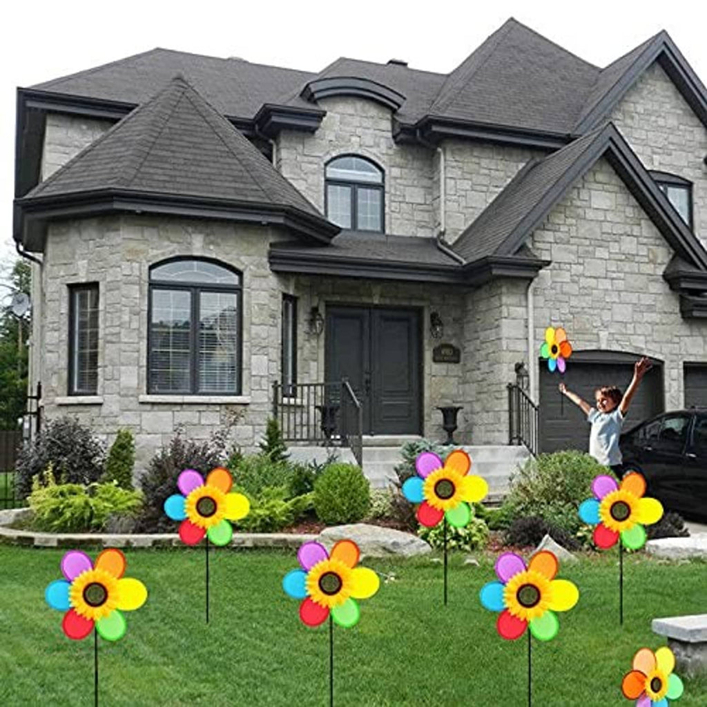 Colorful sunflower pinwheel windmills on black stakes in a front yard