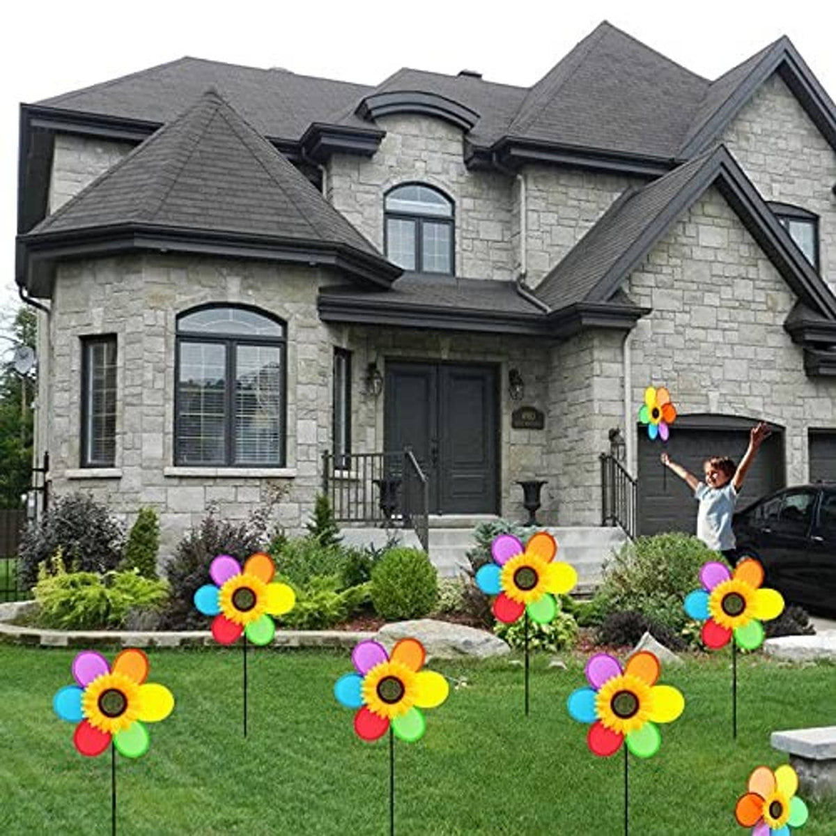 Colorful sunflower pinwheel windmills on black stakes in a front yard