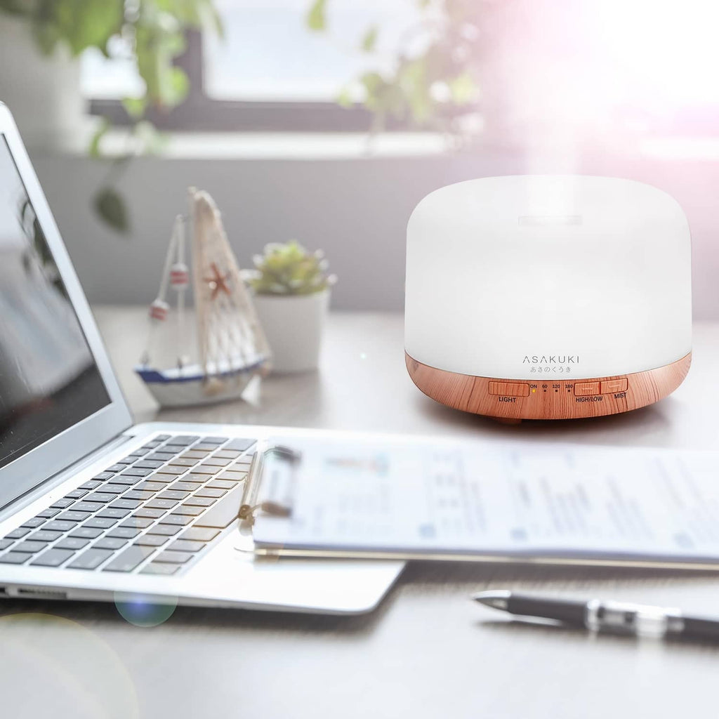 Essential oil diffuser on a desk with white top and orange wood base