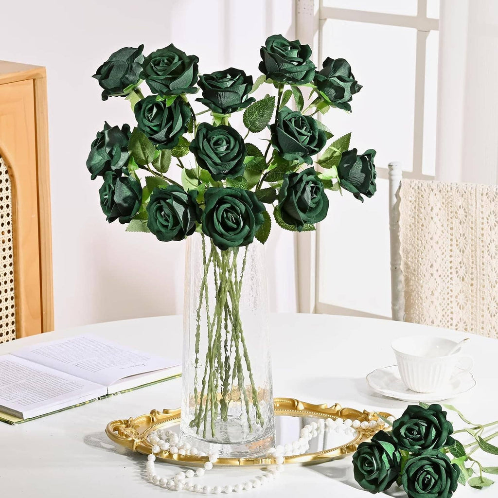 Dark green artificial rose bouquet in a clear vase with long stems on a table tray