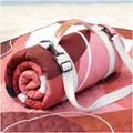 Red waterproof beach blanket rolled with carrying straps and buckles.