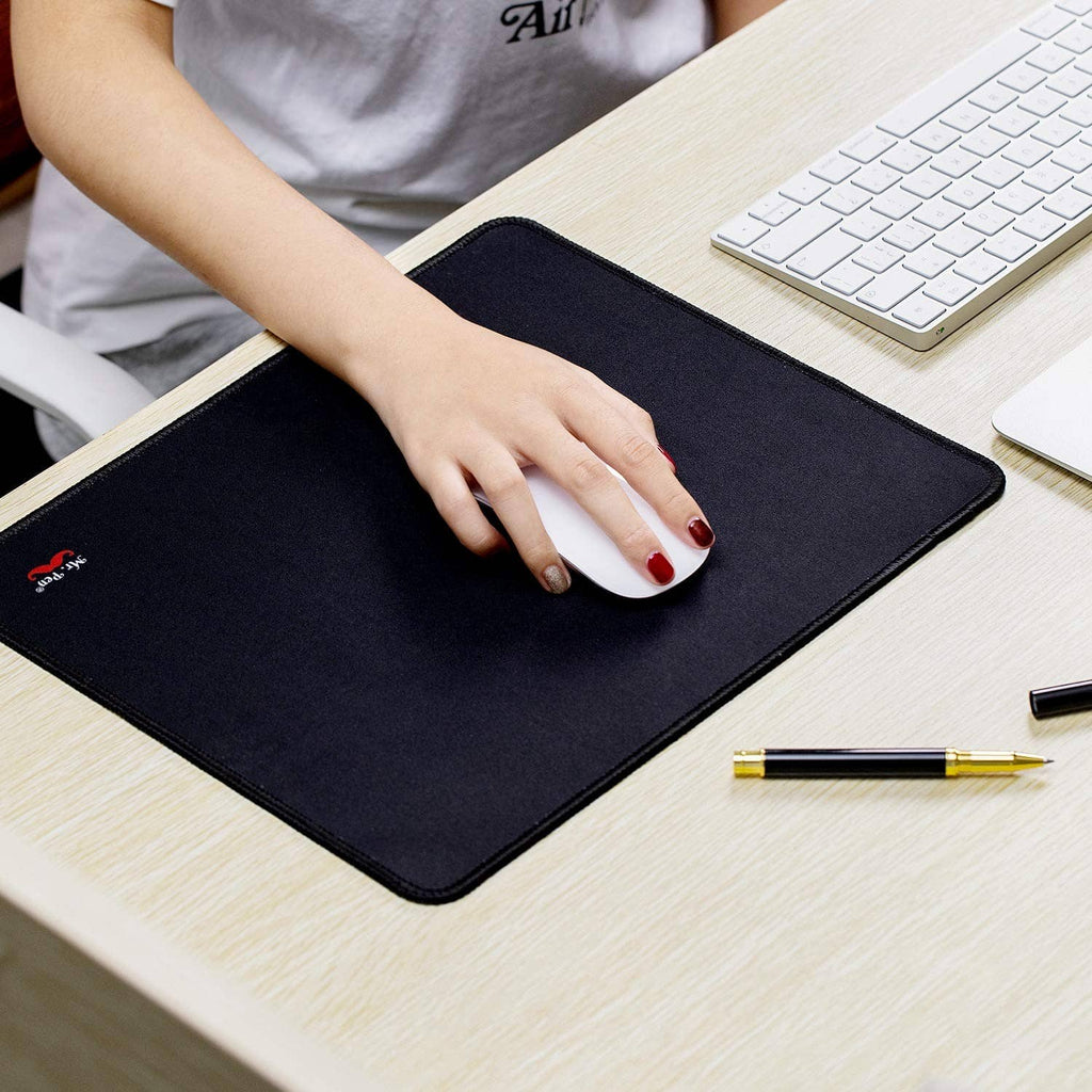 Black rectangular mouse pad with stitched border, hand using a white mouse.
