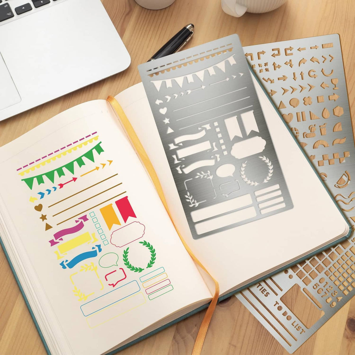 Silver metal stencils laid over open notebooks, showing icons and calendar linework