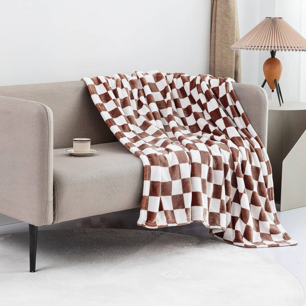 Checkerboard flannel throw blanket draped over sofa arm, coffee-brown and white