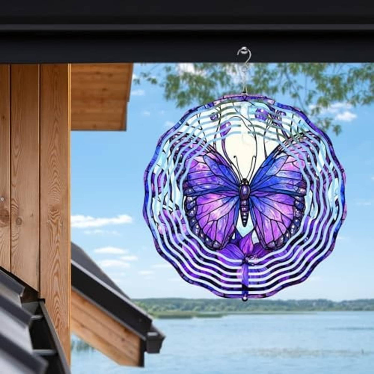 Purple butterfly wind spinner with white spiral rings suspended near house and water view
