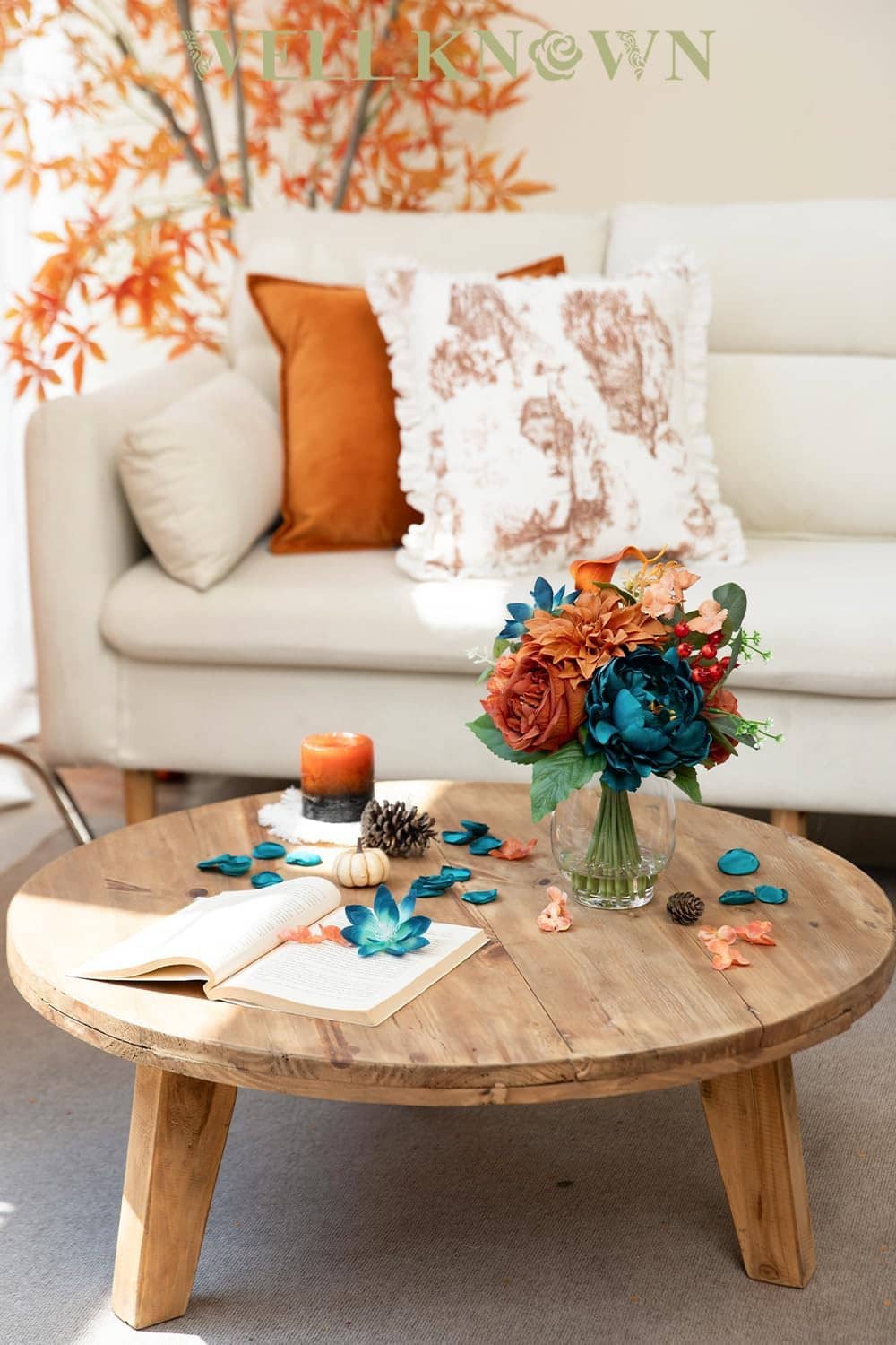 Small clear glass vase holding teal and orange faux peony-dahlia bouquet