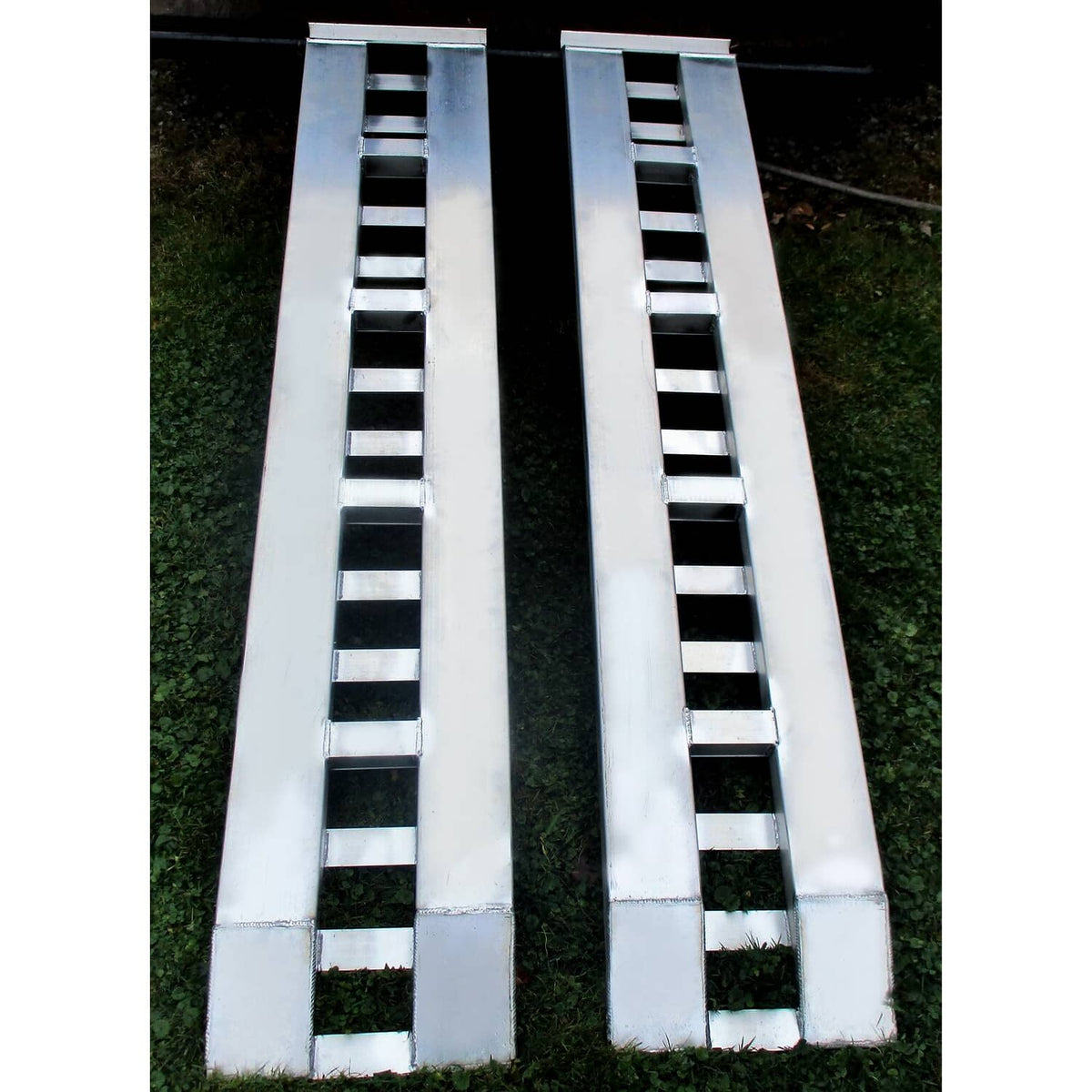 Top view of two aluminum trailer ramps with ladder traction rungs