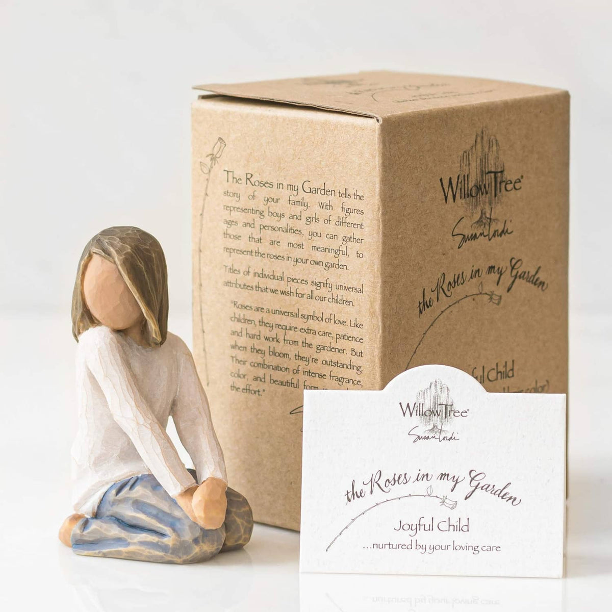 Child figurine kneeling beside a Willow Tree gift box and card.