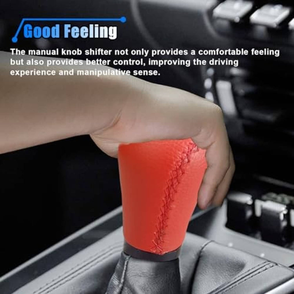 Red leather shift knob held in a hand, stitched grip over black boot