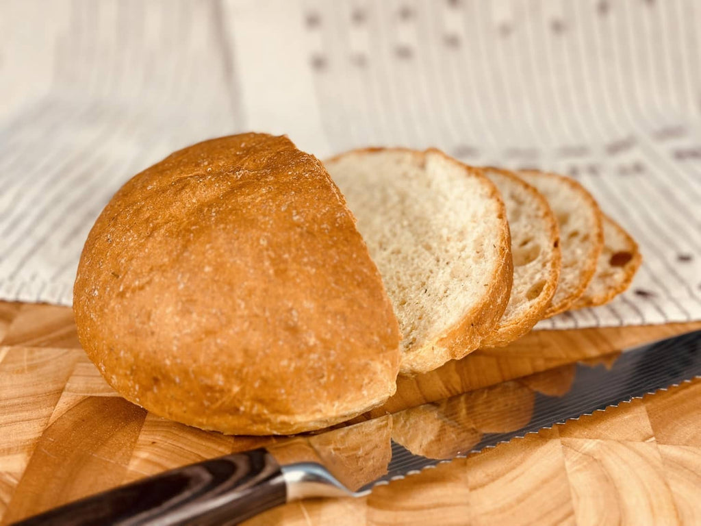 Round potato bread rolls with sliced pieces on a wood board and knife