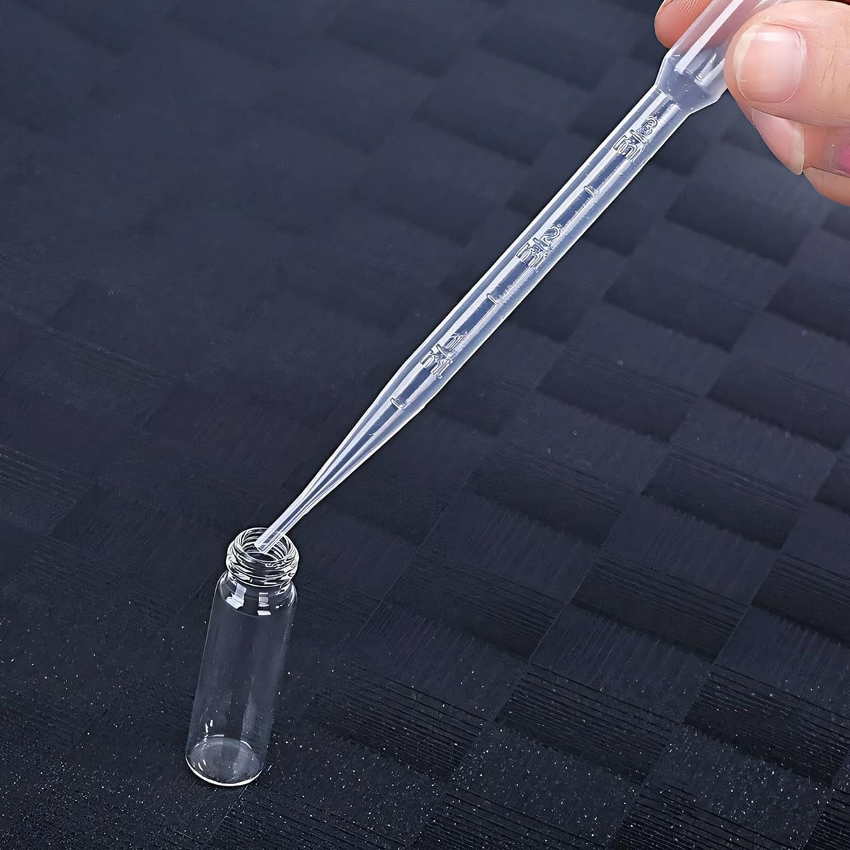 Clear extraction syringe nozzle dispensing into small perfume bottle