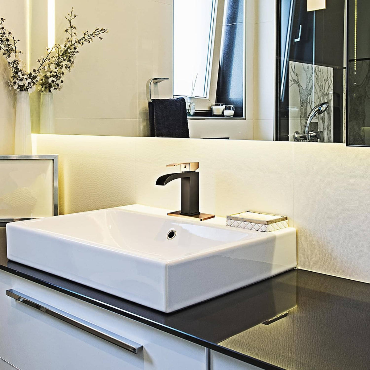 Black and gold waterfall bathroom faucet on white countertop sink