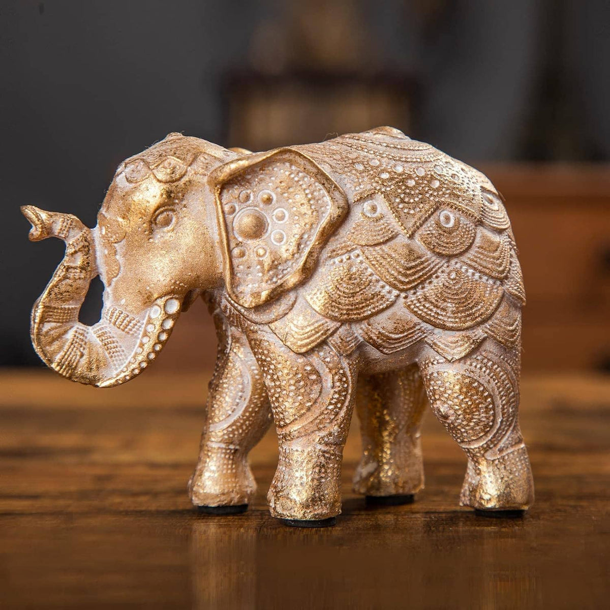 Gold elephant figurine with raised trunk, ornate carved pattern, standing.