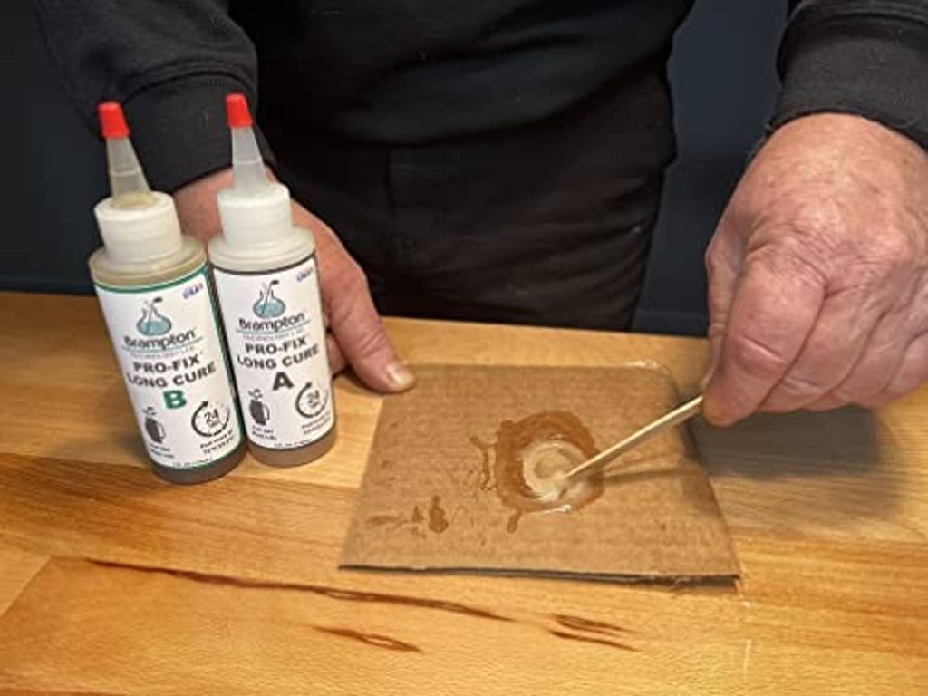 Hands applying epoxy from small bottles A and B onto a wooden golf shaft