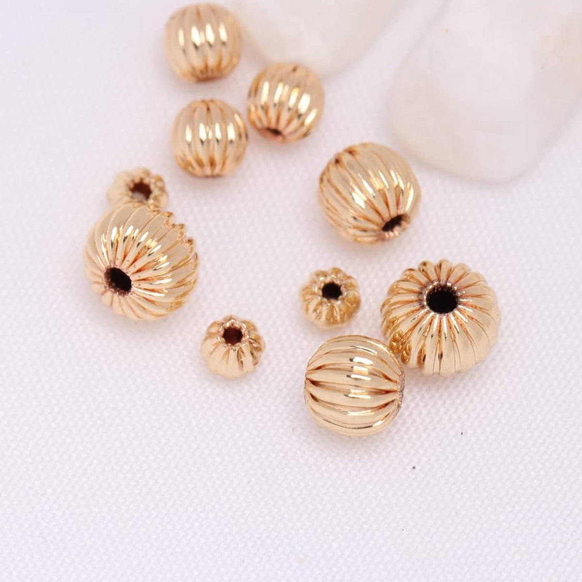 Assorted gold-tone ribbed round beads with dark center dots, scattered