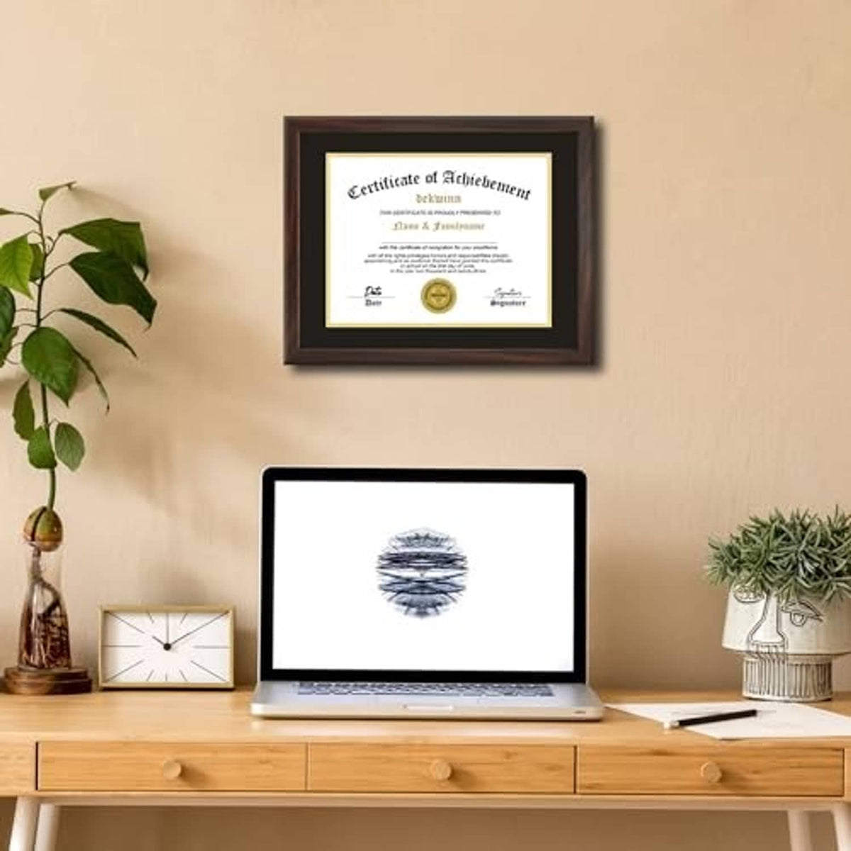 Walnut diploma frame with black mat and gold inner border, hanging above a desk