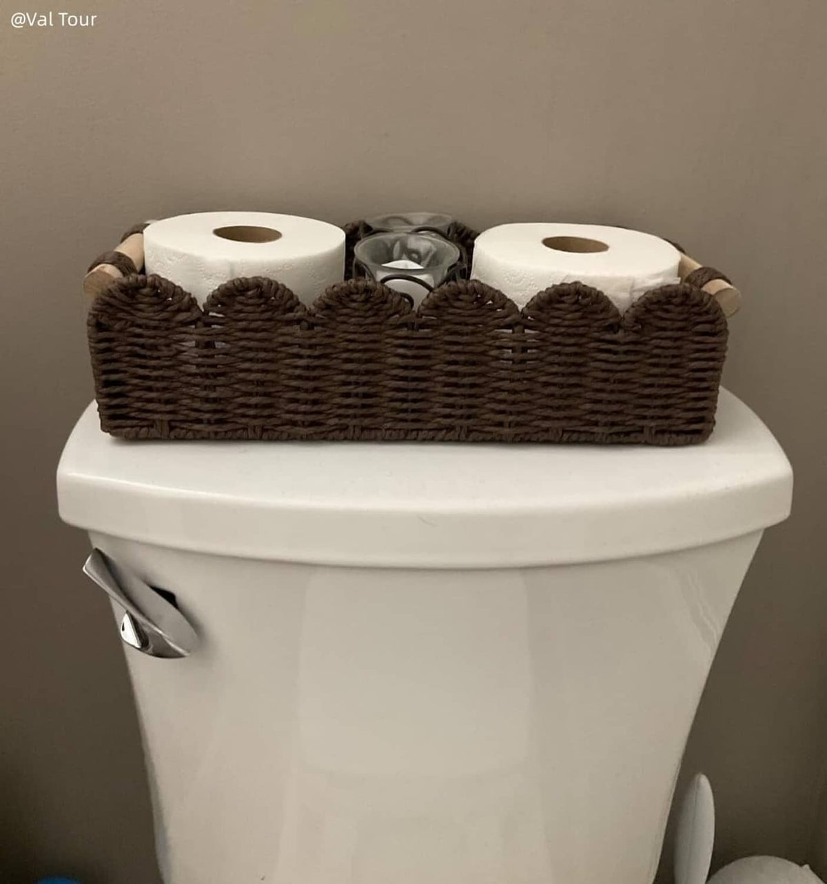 Brown woven toilet paper holder with scalloped edge and three paper rolls on toilet