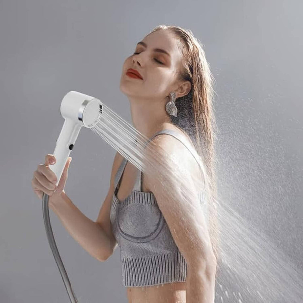Portable shower head spraying water over shoulder with white pump and flexible hose