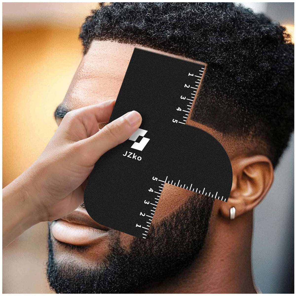 Black hairline shaping card with ruler template placed across hairline near ear