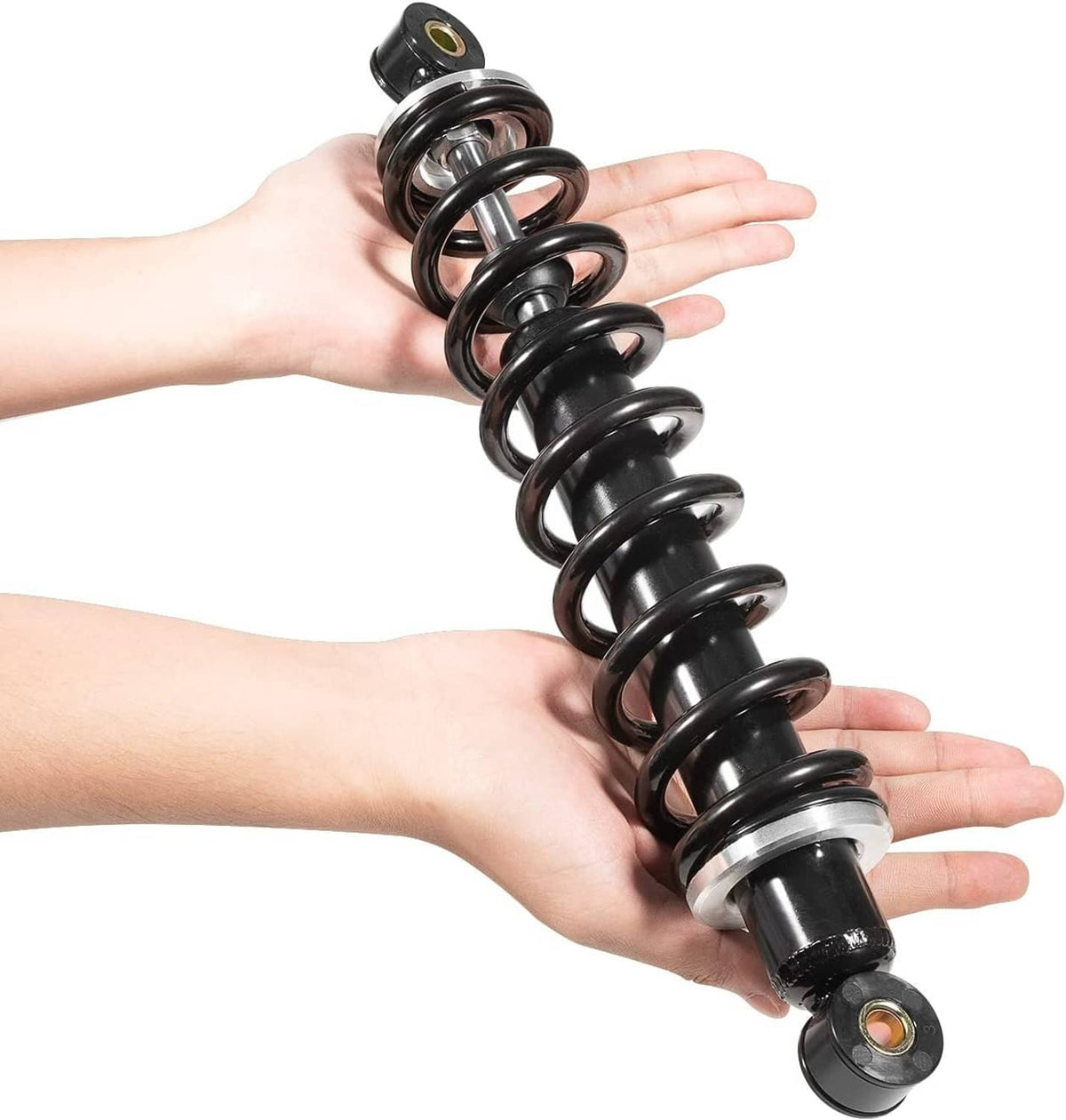 Two front shock absorbers held in hands, black coils with silver mounting hardware