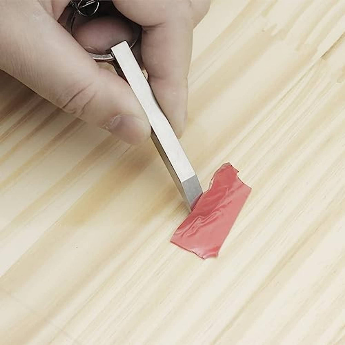 Mini prybar lifting a red seal from a surface