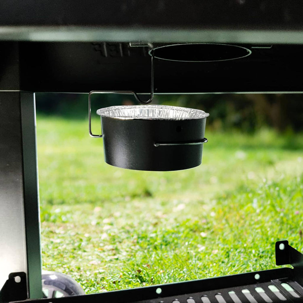 Black grease cup holder with metal clip holding an aluminum foil liner on a gas grill