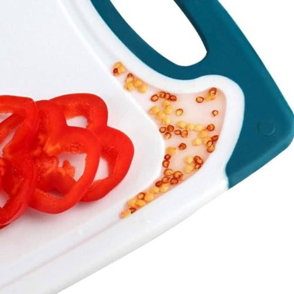 Teal-handled plastic cutting board with white surface, showing chopped red peppers