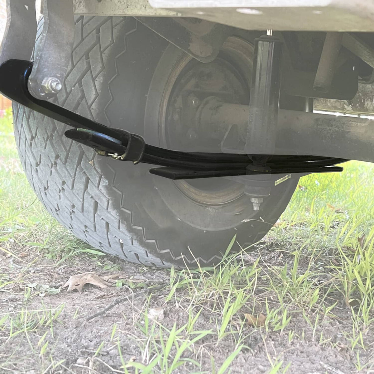 Golf cart rear wheel area with black leaf spring assembly attached under the frame