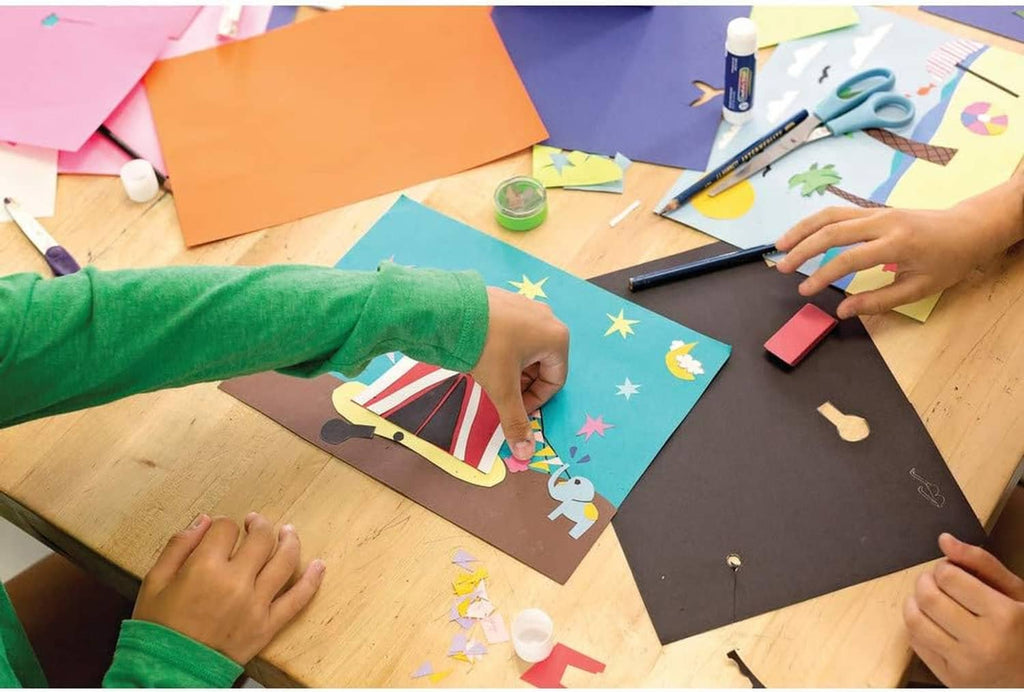 Crafting hands arranging colorful construction paper pieces on a desk