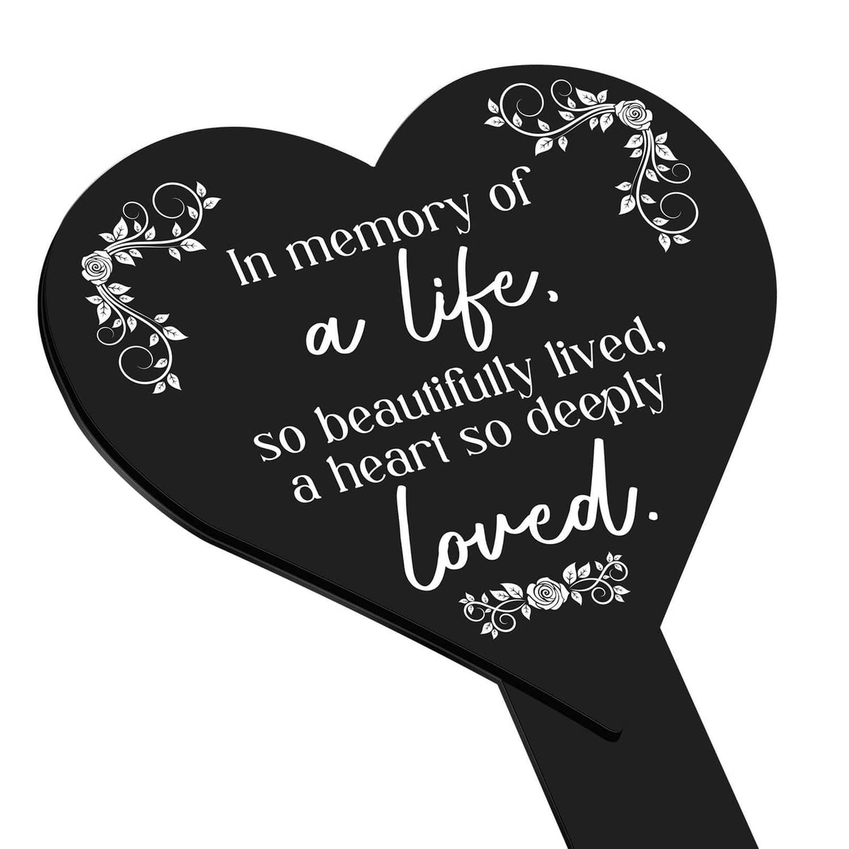 Heart-shaped black memorial plaque with white lettering and decorative floral wreath.