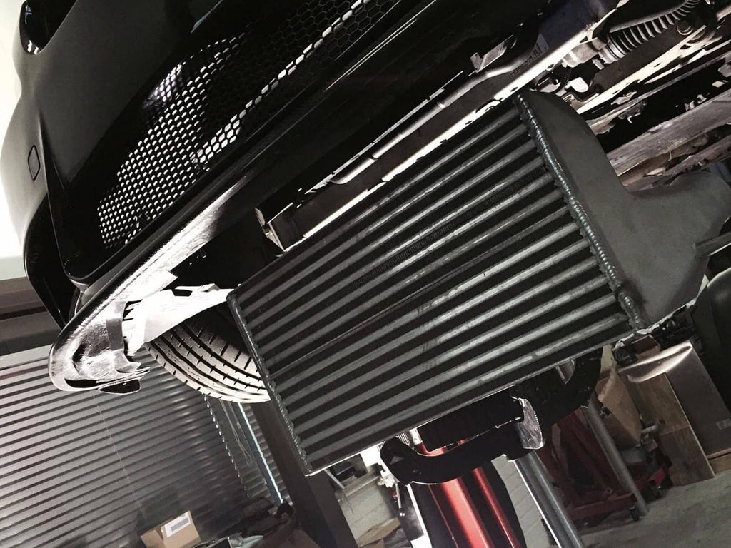Installed front-mount intercooler showing black fin core behind the front grille
