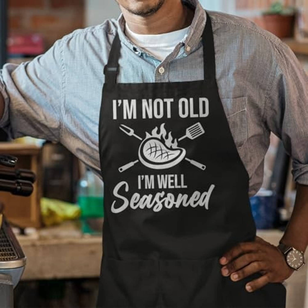 Black cooking apron on man with 'I'm not old, I'm well seasoned' design