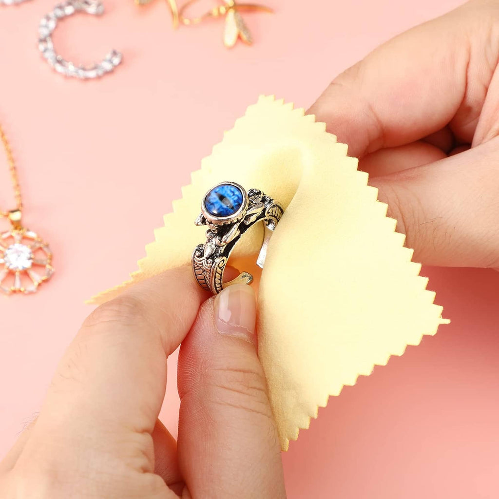 Yellow jewelry cleaning cloth polishing a silver ring with blue gemstone