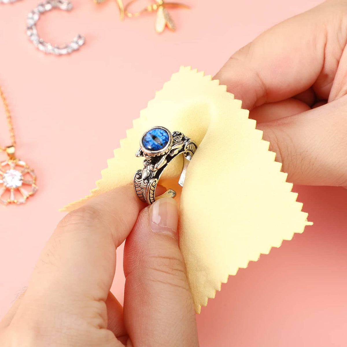 Yellow jewelry cleaning cloth polishing a silver ring with blue gemstone