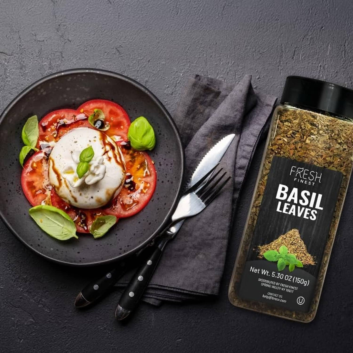 Dried basil leaves jar next to a dish of tomato and basil with melted cheese
