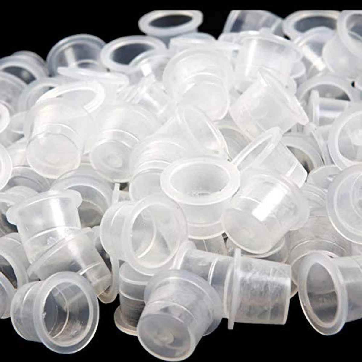 Disposable clear plastic tattoo ink caps, small round open tops, close-up pile