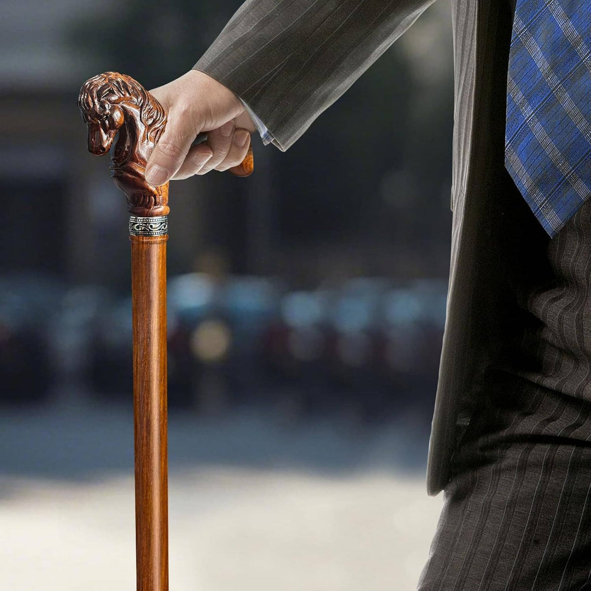Wooden walking cane with carved horse head handle, hand gripping the shaft