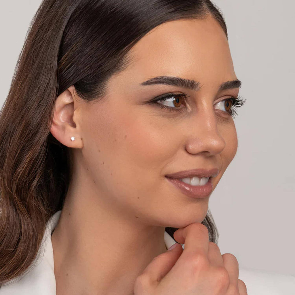 Woman wearing a small round clear stud earring on the ear lobe
