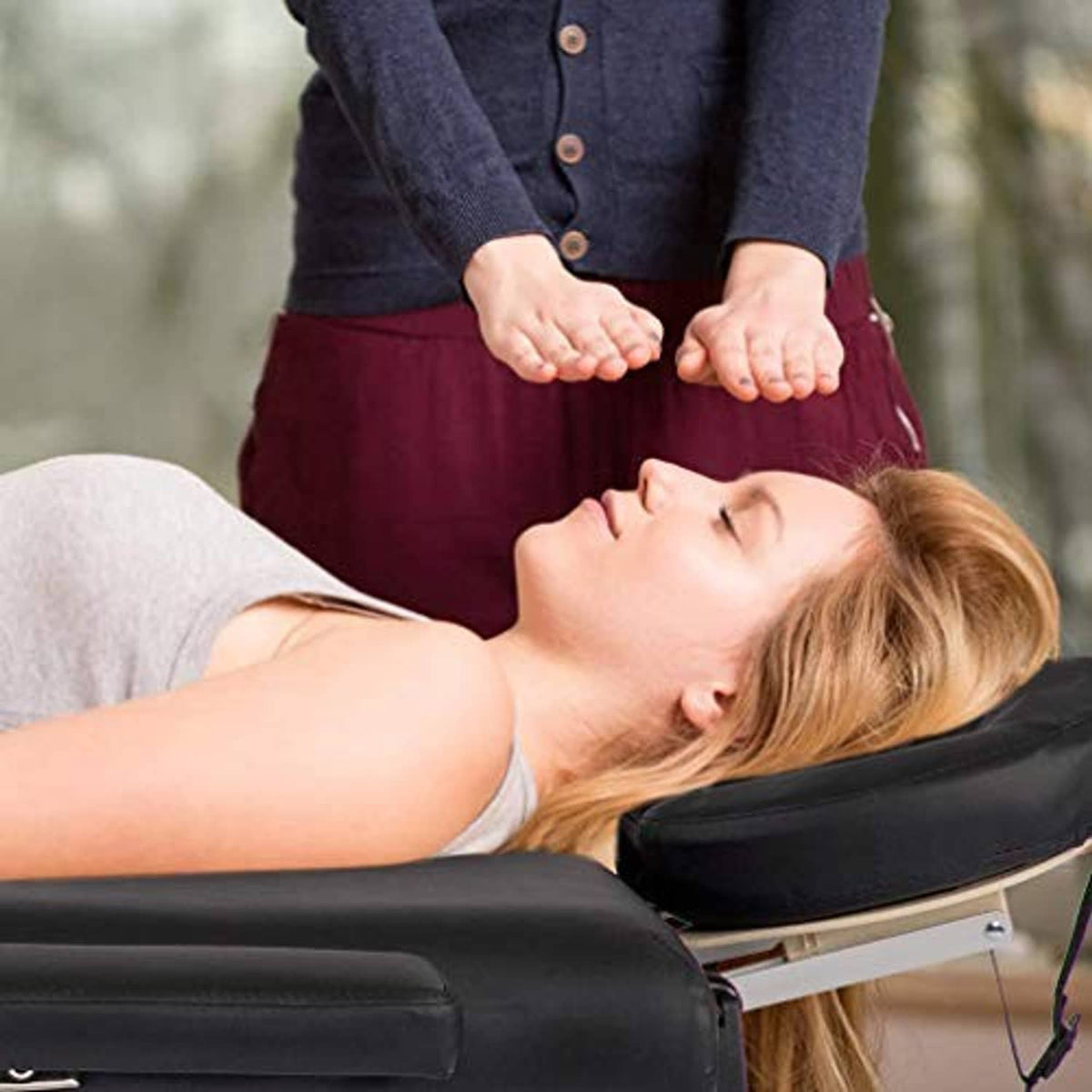 Black massage table with padded headrest and cushioned surface for body massage