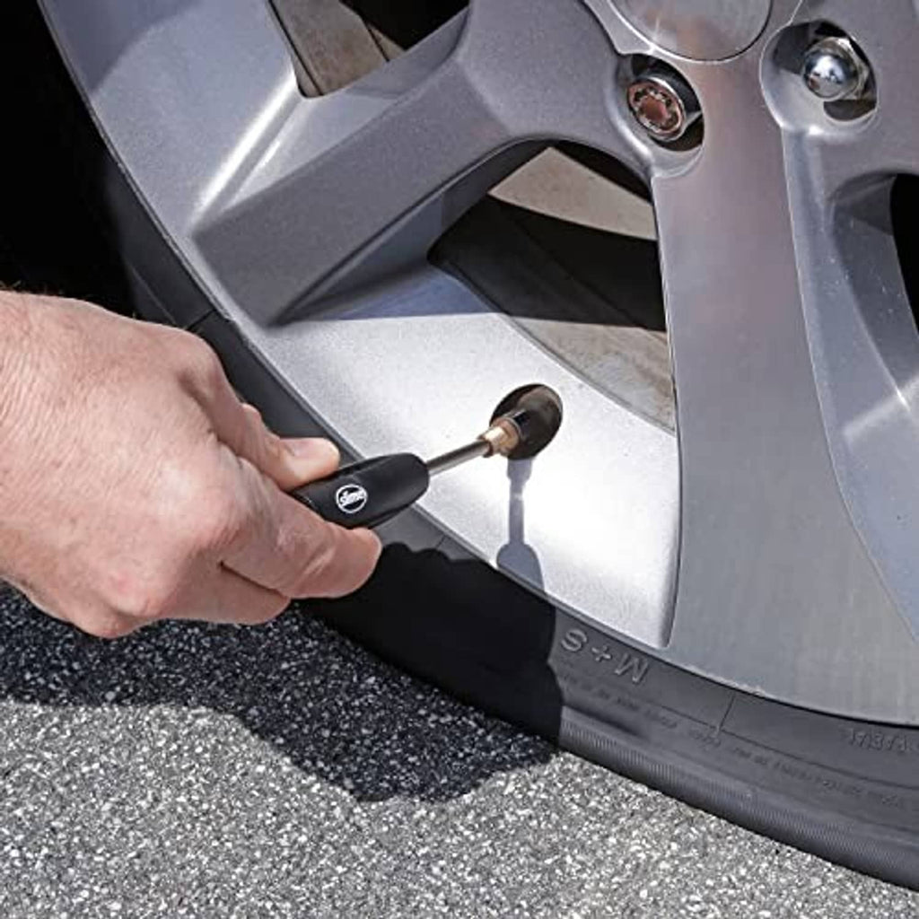 Valve core tool in use: black handle turning a wheel valve core