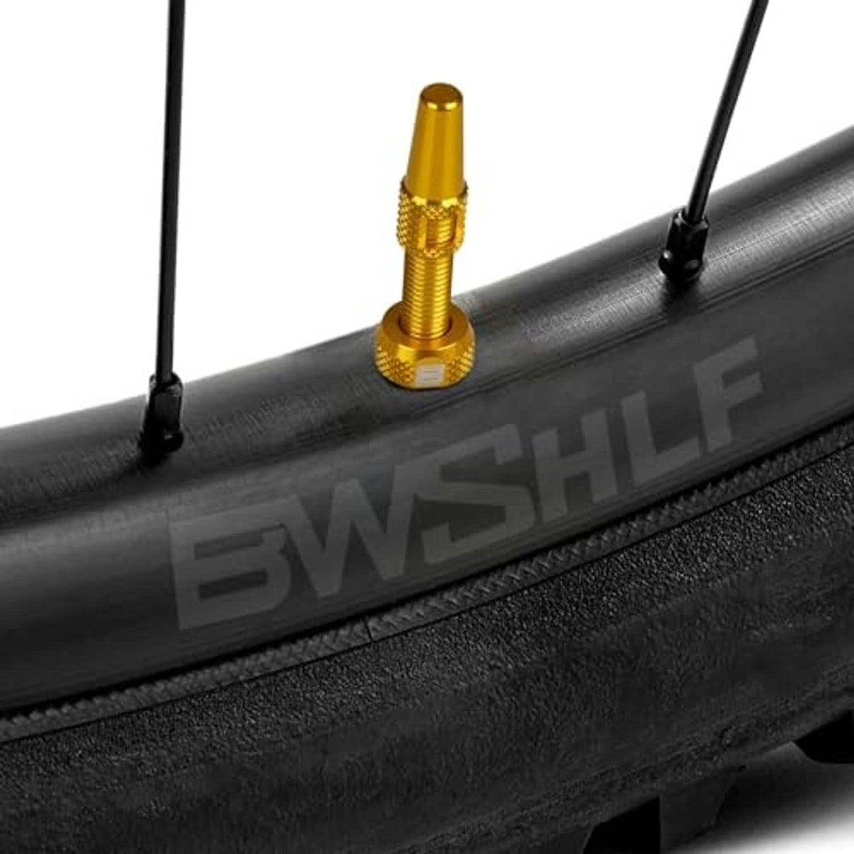 Golden Presta valve stem installed on black rim, tubeless valve detail