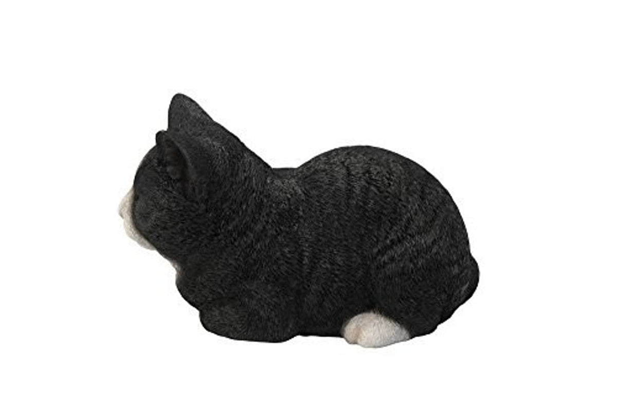 Sleeping cat statue in black with white paw accents, curled on side view
