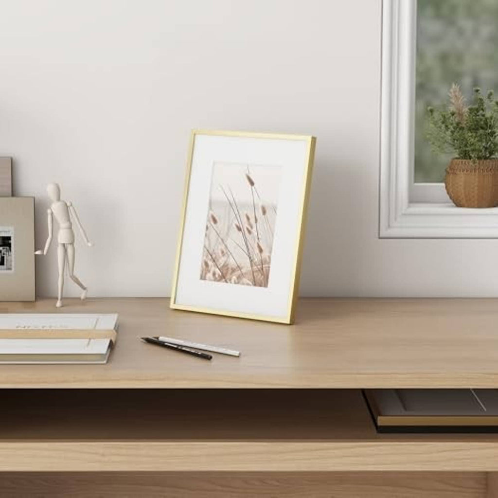 Gold 5x7 metal photo frame standing on a table with a landscape photo